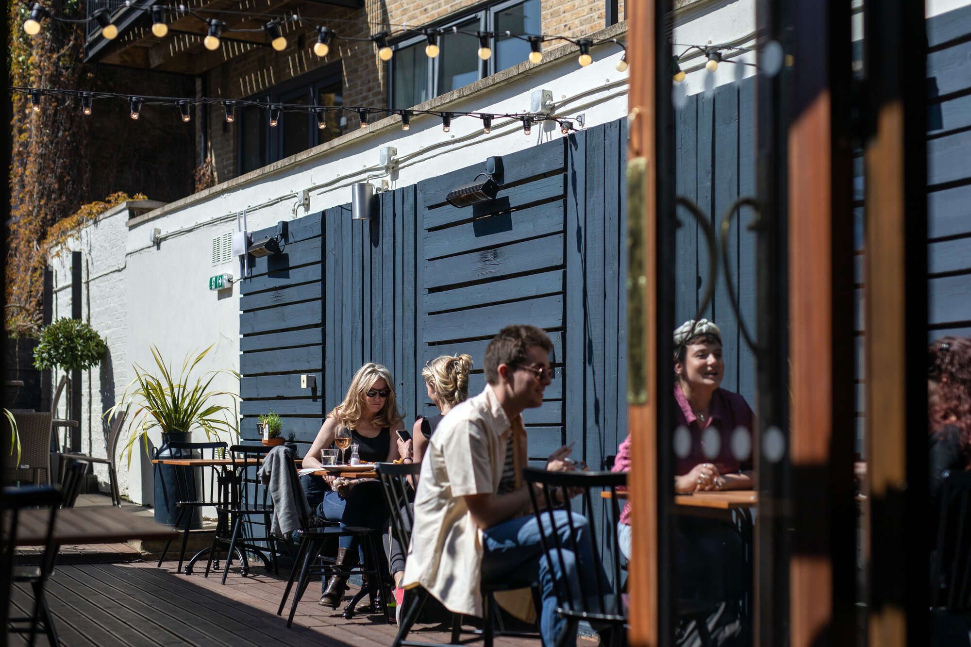 Outside seating area of Cock Tavern with people sat at tables.