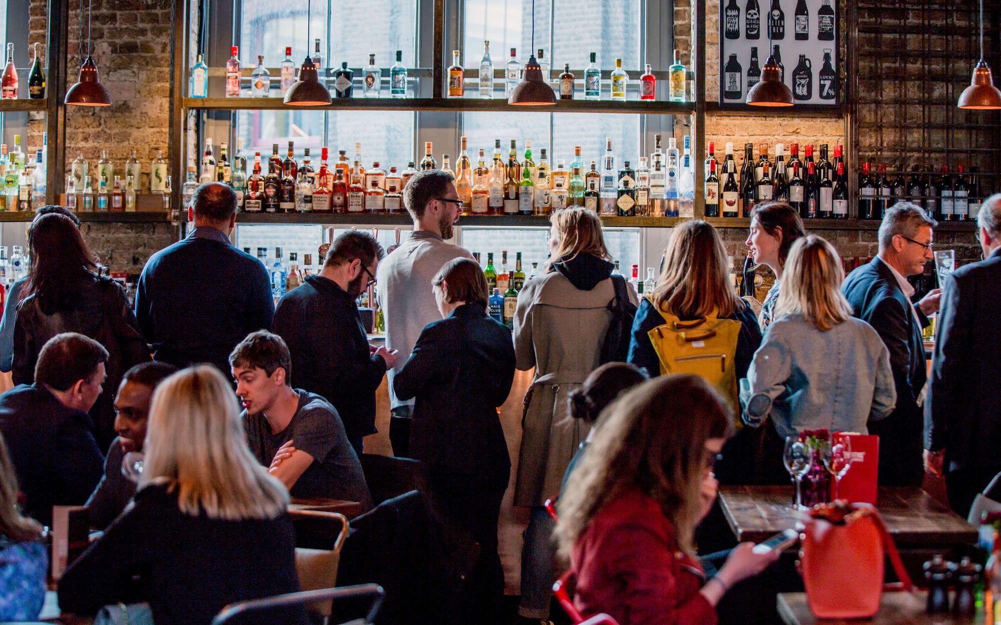 Young's pub with groups of people ordering drinks at the bar and sitting at tables