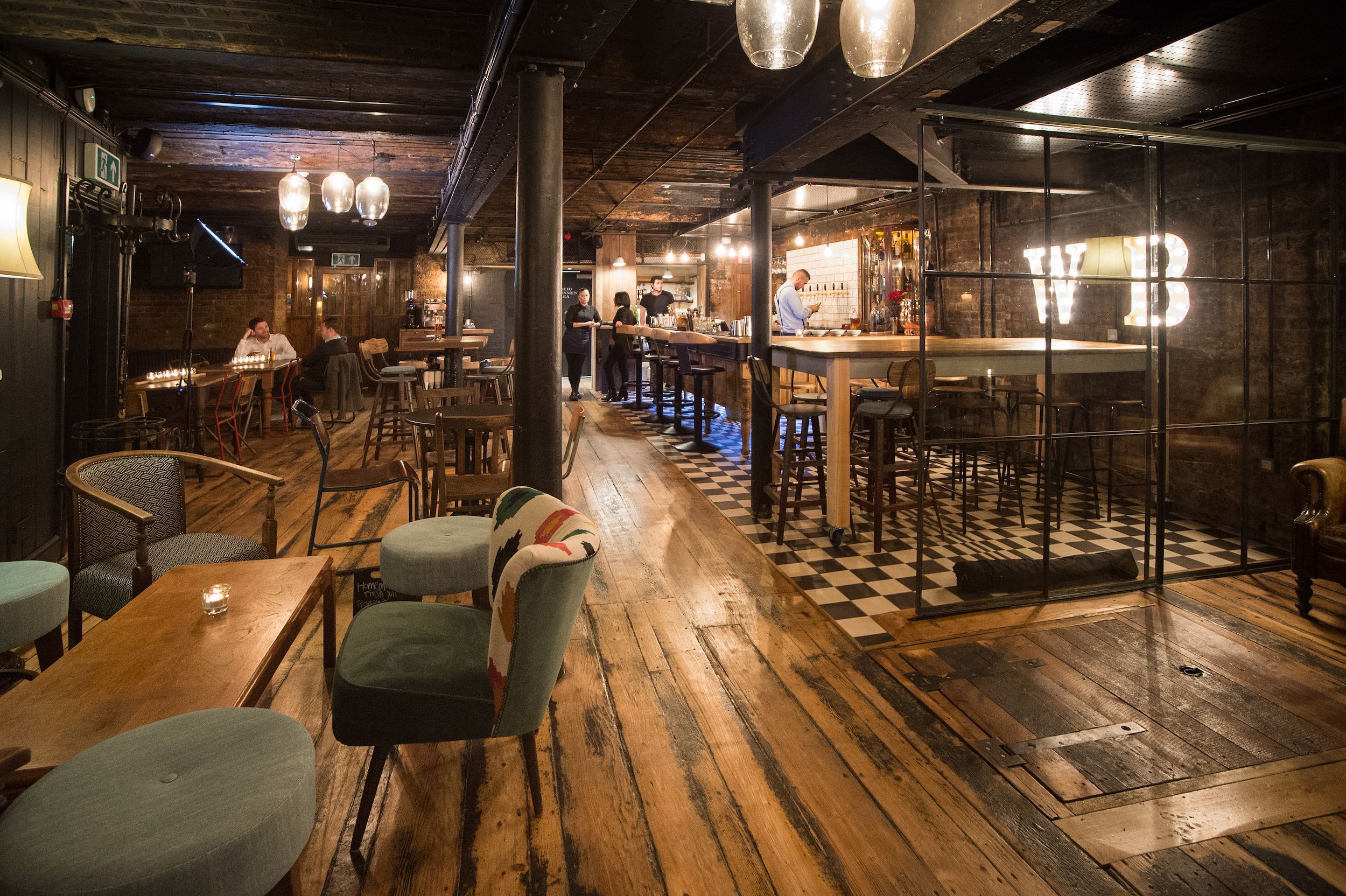 Young's pub interior with wooden tables, comfy chairs, checkered floor, and a large bar area