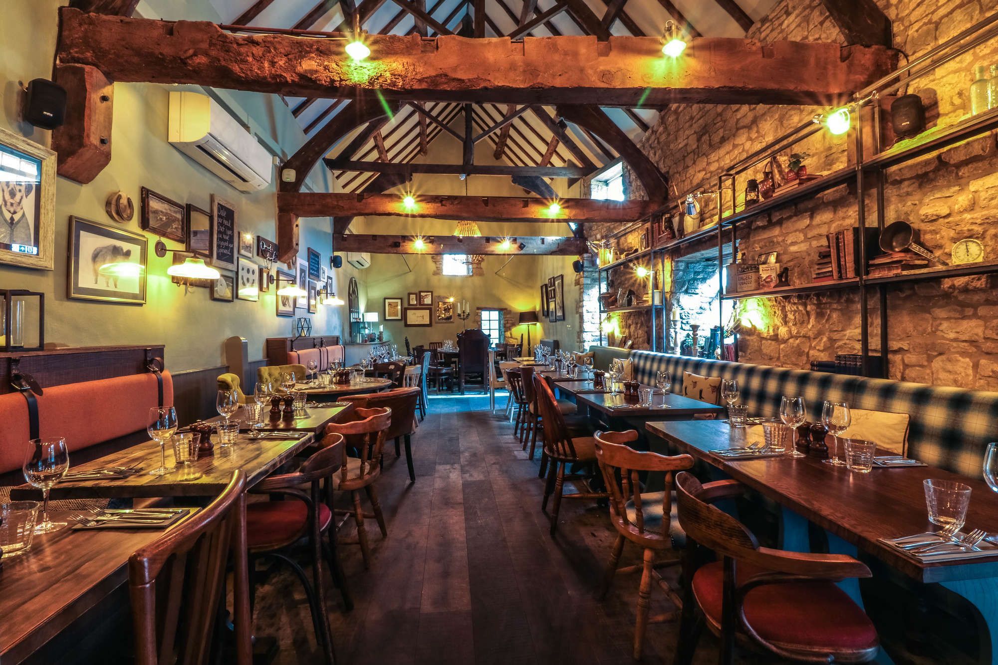 pub interior with wooden ceiling beams, tables, chairs, and checkered booths