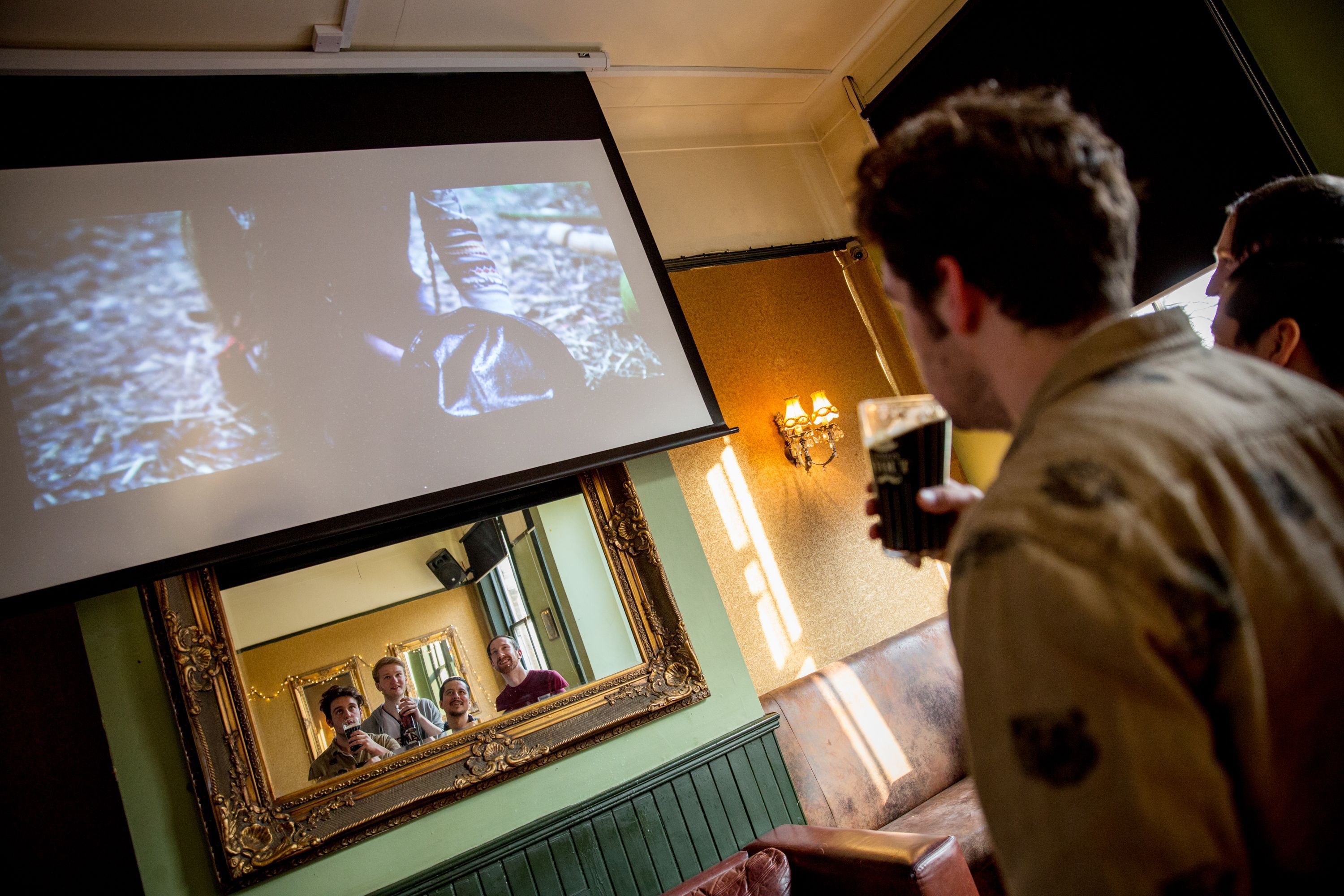 friends taking a mirror selfie under a screen playing a film