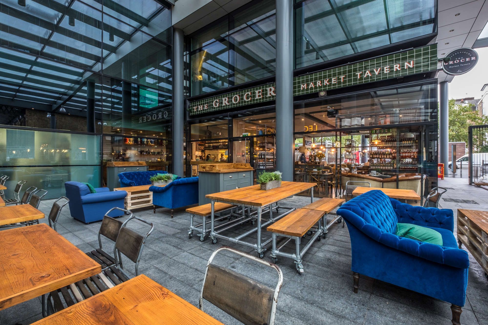 outdoor covered pub seating area with picnic tables and comfy blue chairs