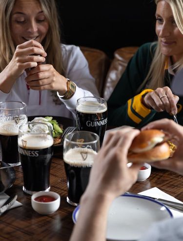 friends sharing Guinness and food at a Young's pub