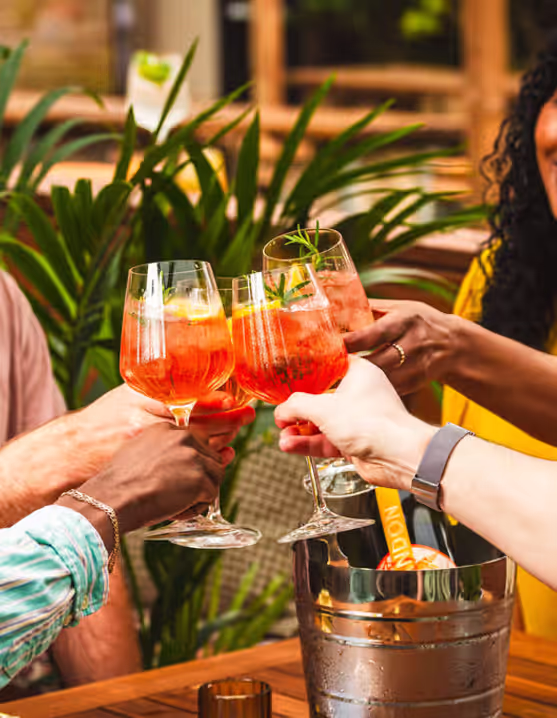 friends clinking Aperol spritz glasses together