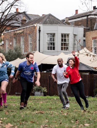 group of people wearing rugby jerseys and running in a yard